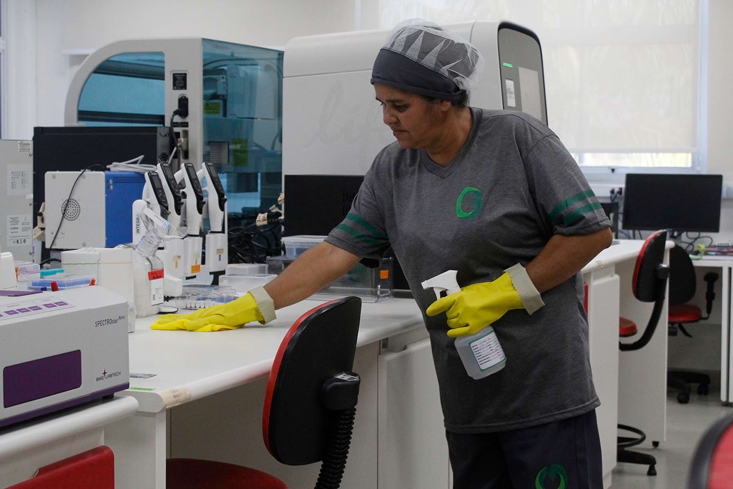 Funcionária limpando laboratório com eficiência, ilustrando custos operacionais em contraste com despesas.