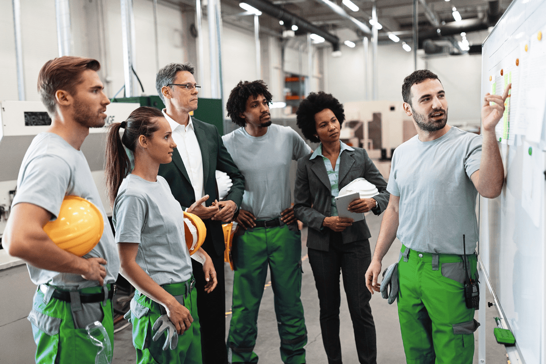 Instrutor e trabalhadores em ambiente industrial discutindo segurança